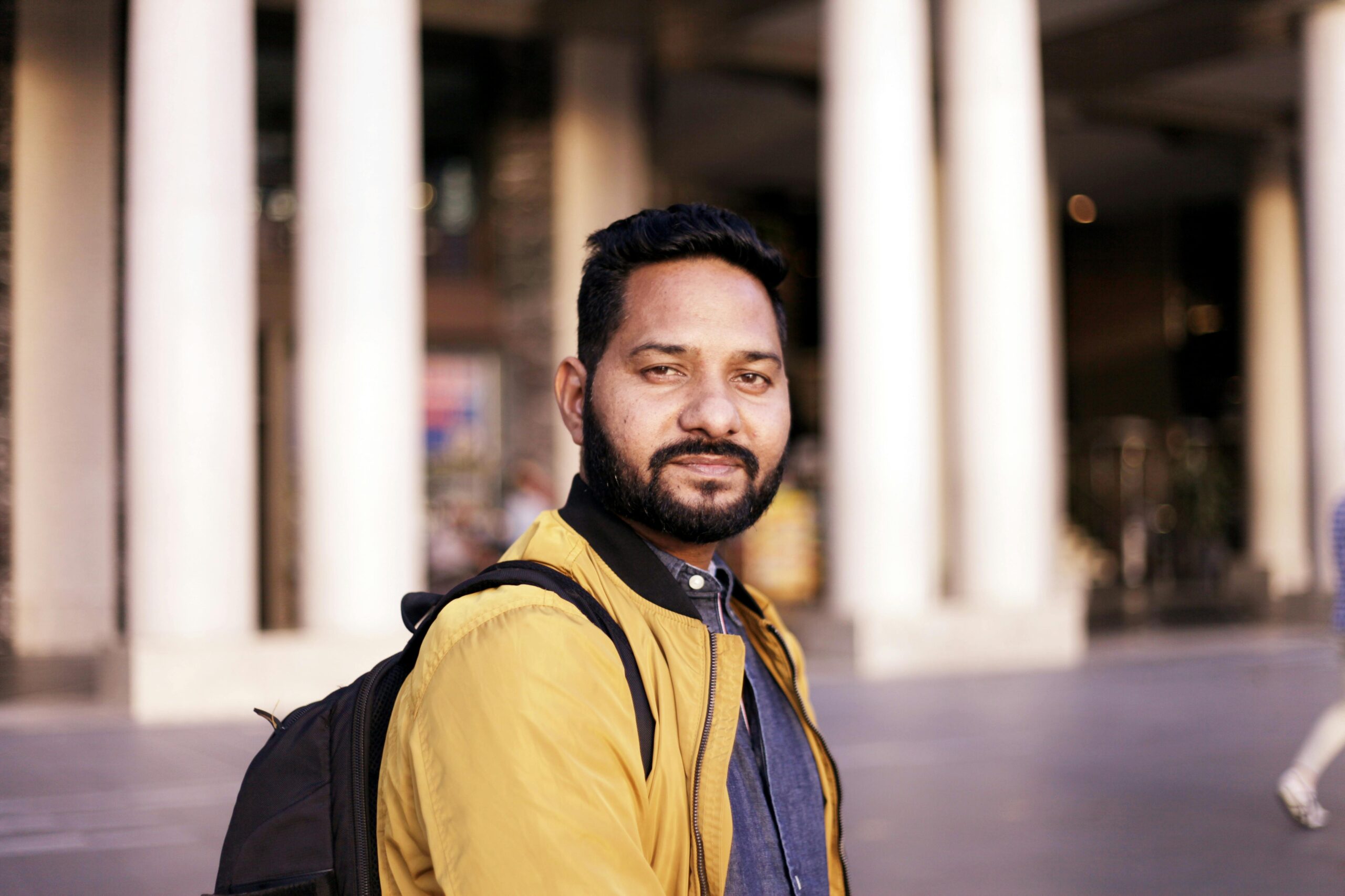 Candid shot of a young man with a backpack in an urban setting with columns.